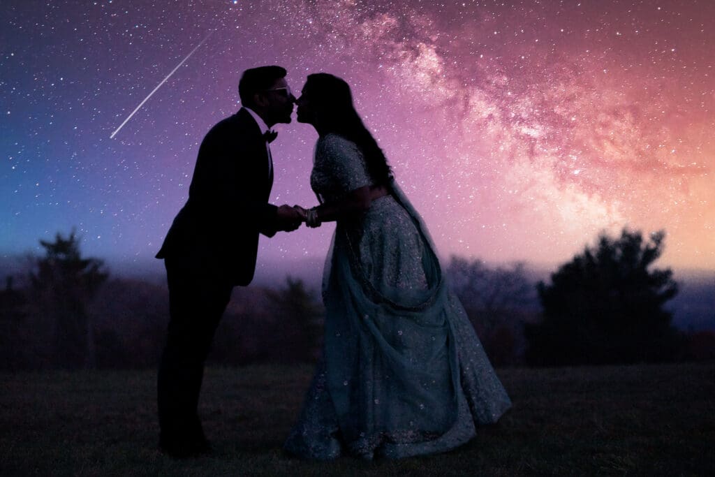 Couple in Indian bridal attire kissing under the night sky