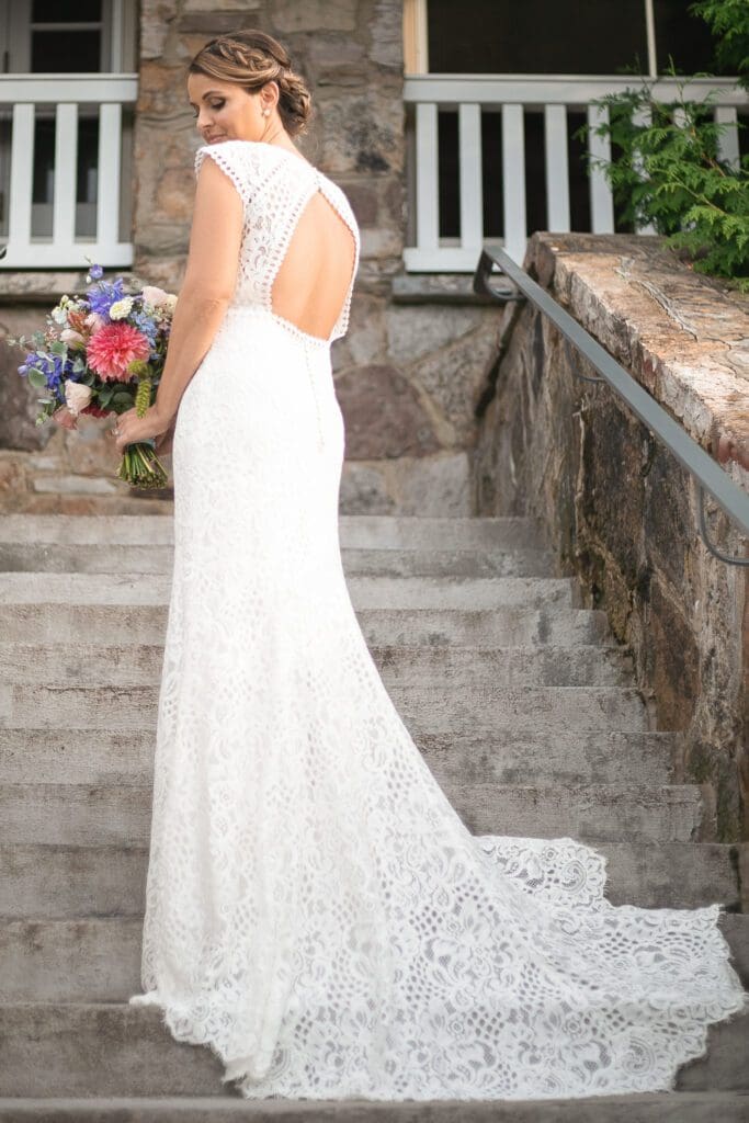 Bride standing on stone stairs with wedding dress spread out showing off the design.