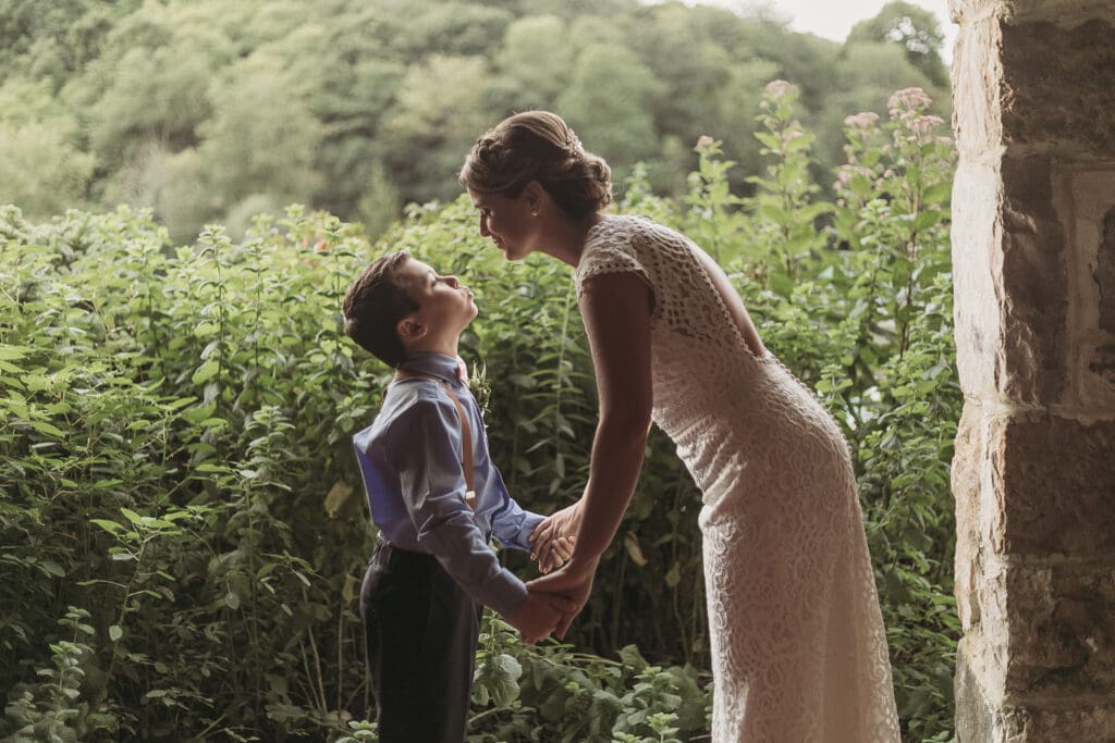 Bride and mother holding her young sons hands in a heartwarming moment.