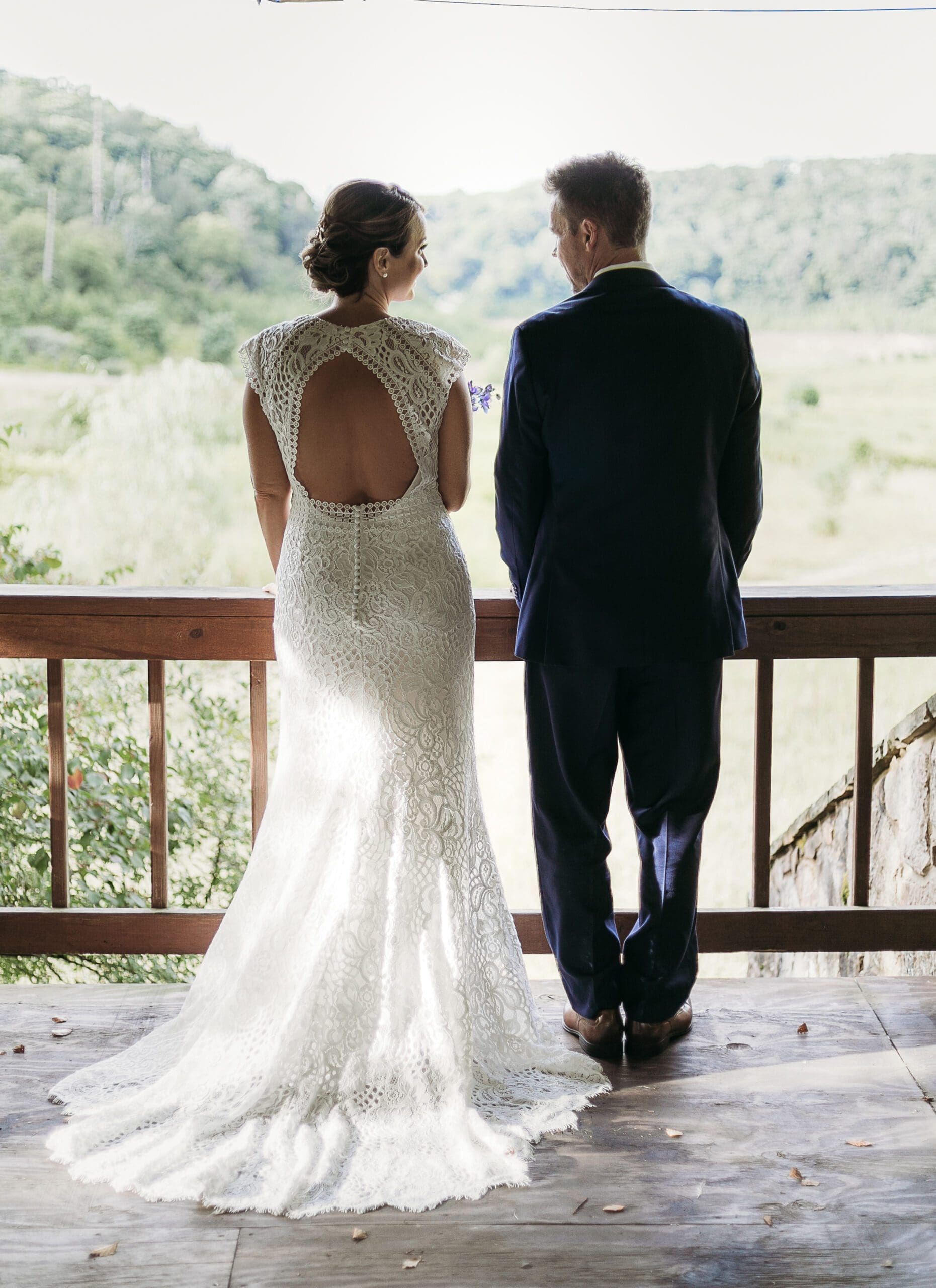 Bride and Groom standing under gazebo looking out on the green lush mountains.