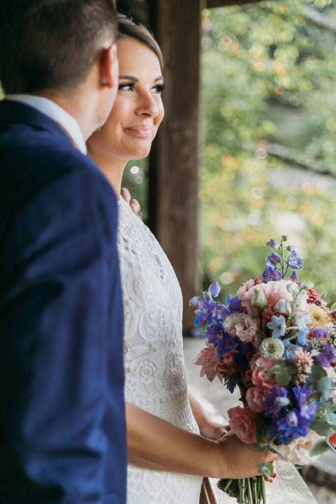 Bride and Groom standing under gazebo looking out on the green lush mountains.