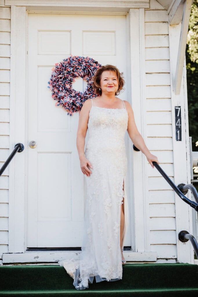 Couple eloping at a small chapel in the blue ridge mountains standing outside the white chapel with lush green landscape.