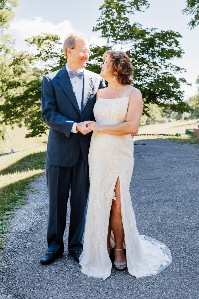 Couple eloping at a small chapel in the blue ridge mountains standing outside the white chapel with lush green landscape.