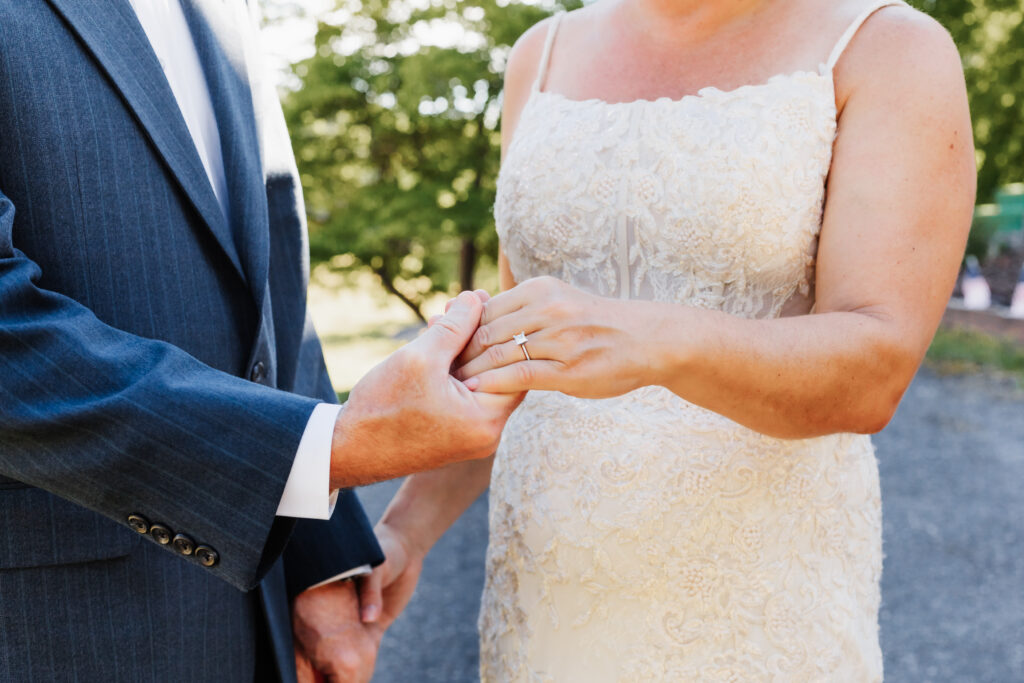 Couple eloping at a small chapel in the blue ridge mountains standing outside the white chapel with lush green landscape.