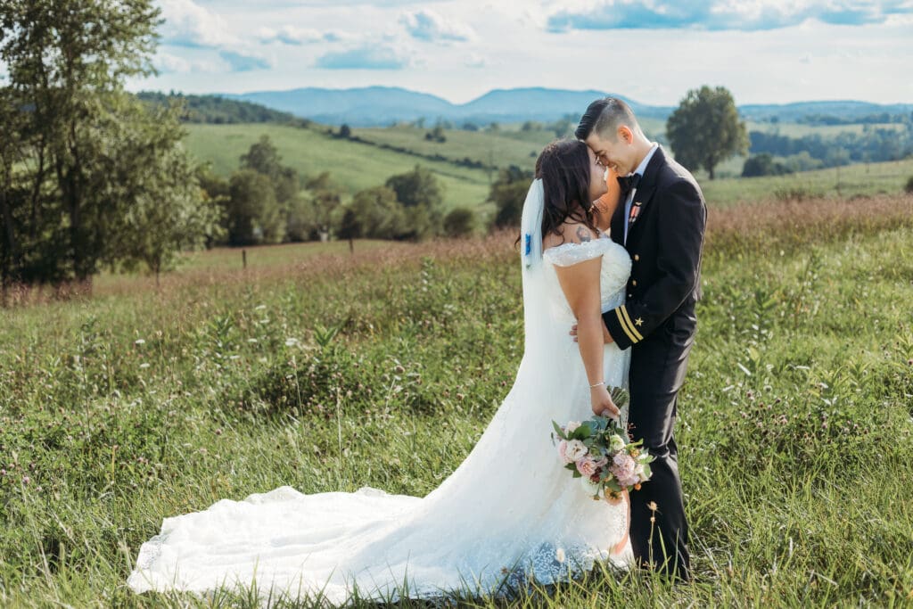Couple getting eloping in a field with trees all green and blue rolling mountains in the distance.