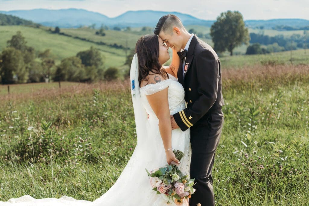 Couple getting eloping in a field with trees all green and blue rolling mountains in the distance.
