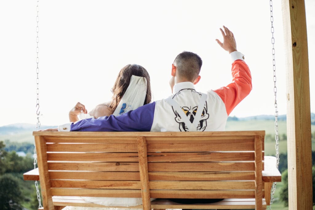 Couple just married sitting on a porch swing with mountains in the distance.