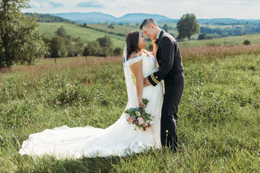 Couple getting eloping in a field with trees all green and blue rolling mountains in the distance.