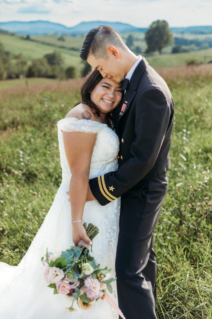 Couple getting eloping in a field with trees all green and blue rolling mountains in the distance.