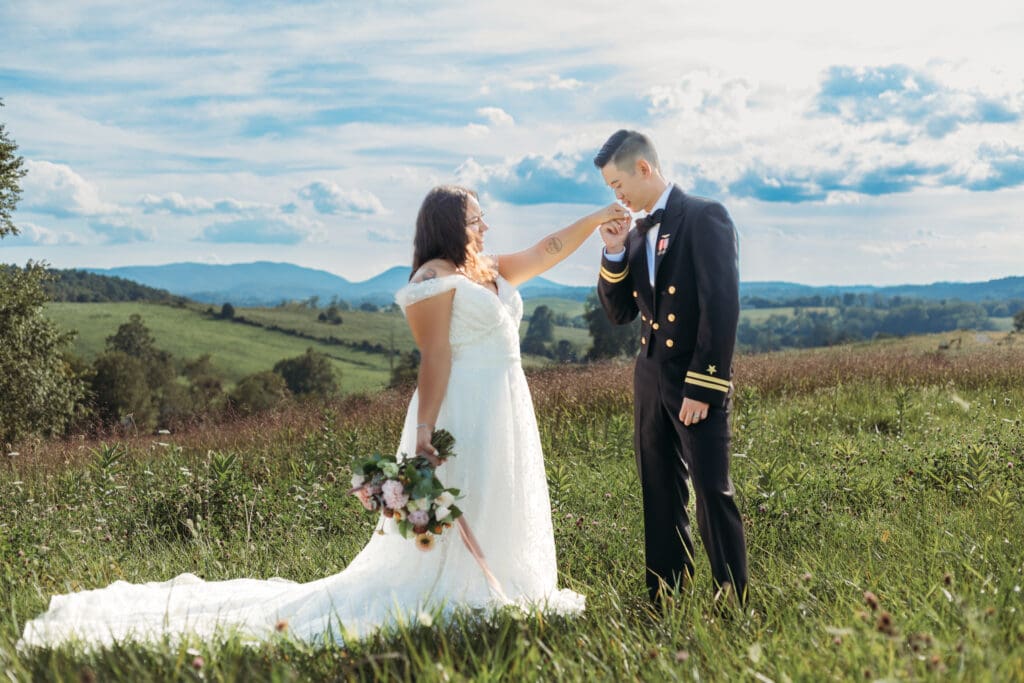Couple getting eloping in a field with trees all green and blue rolling mountains in the distance.