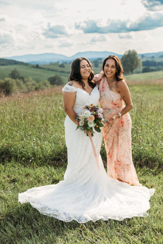 A bride with mom fawning over her in a field of green with rolling green mountains in the background.