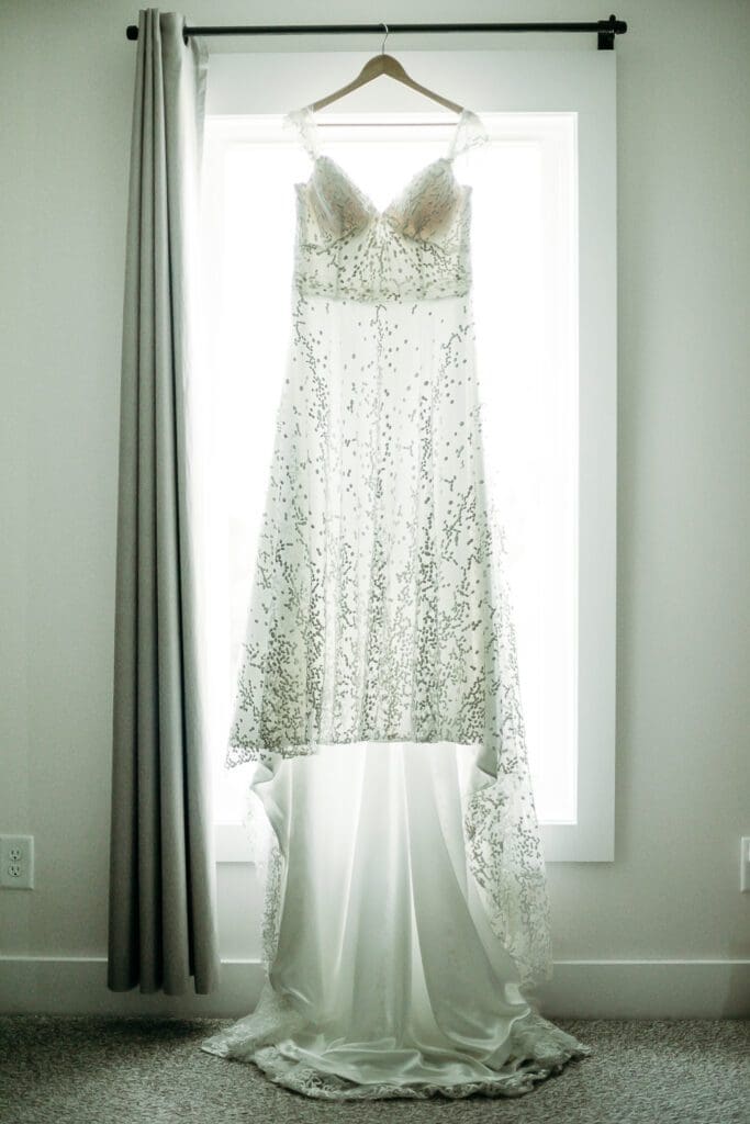 Wedding dress hanging in front of window while being backlit.
