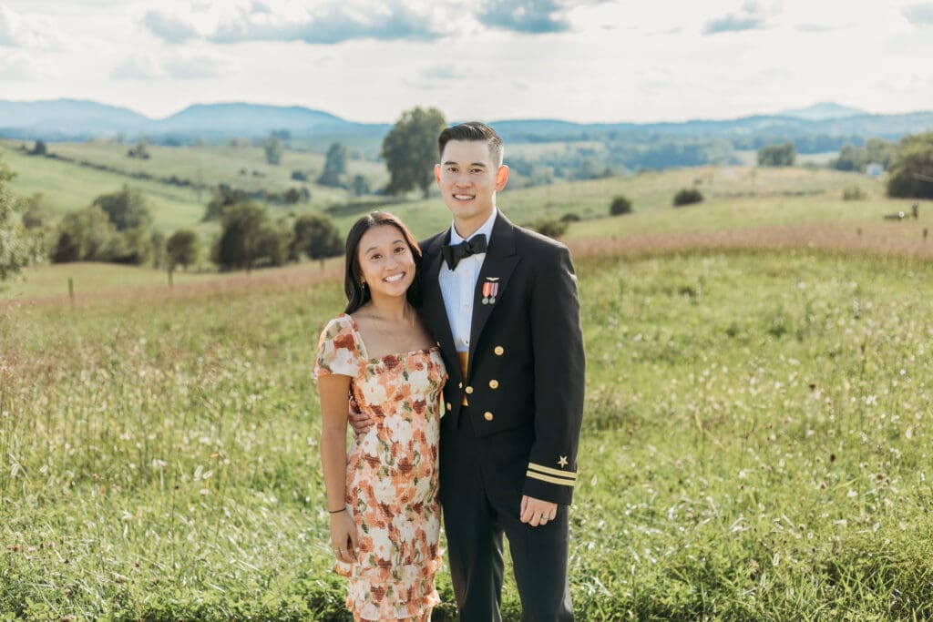 A groom with sister fawning over him in a field of green with rolling green mountains in the background.