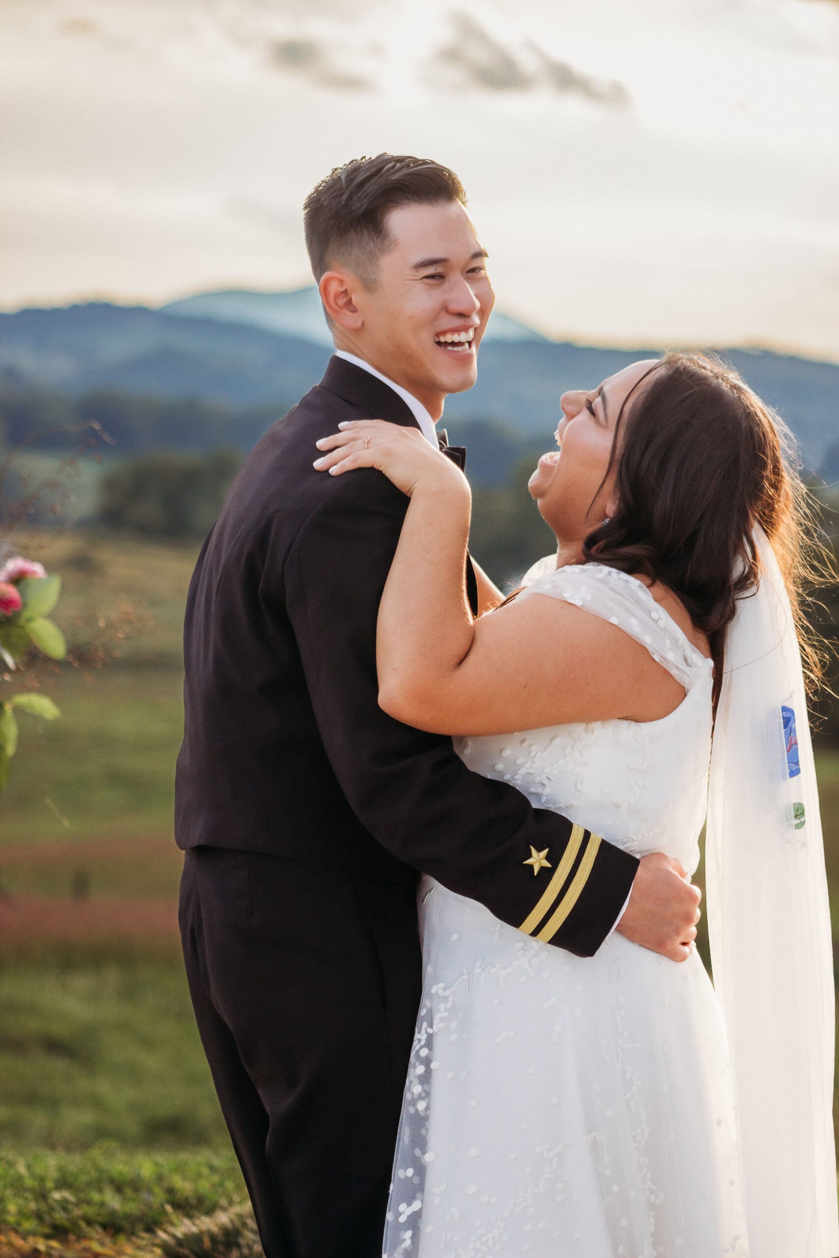 Bride and groom having a first dance at their mountain elopement. They are dancing on a concrete porch with fields of green surrounding them and rolling blue mountains in the distance.