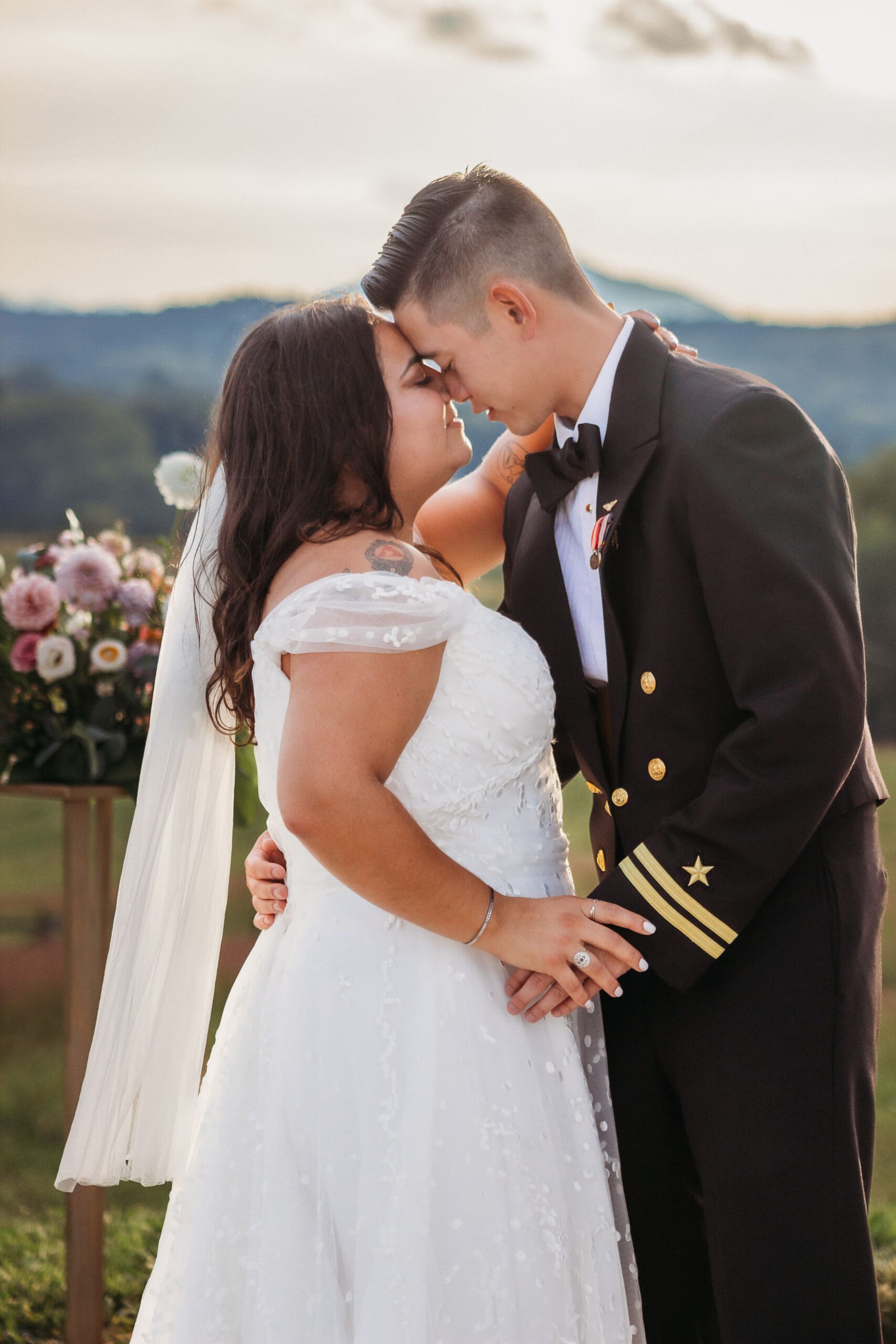 Bride and groom having a first dance at their mountain elopement. They are dancing on a concrete porch with fields of green surrounding them and rolling blue mountains in the distance.