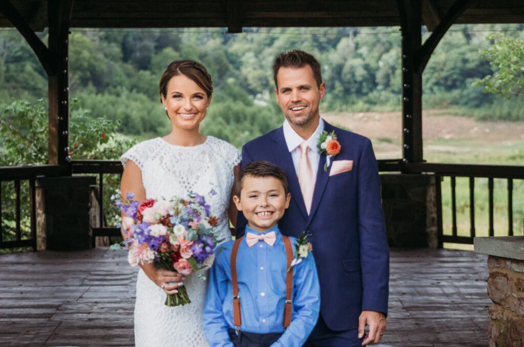 Couple getting married under gazebo eloping in front of the mountains with their son.