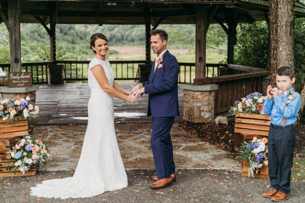 Couple getting married under gazebo eloping in front of the mountains with their son.