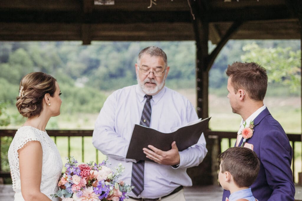 Couple getting married under gazebo eloping in front of the mountains with their son.