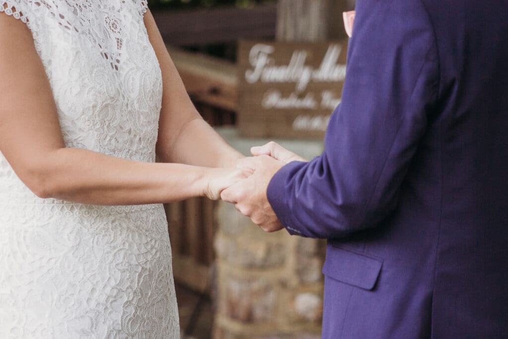 Couple exchanging wedding rings outdoors under gazebo