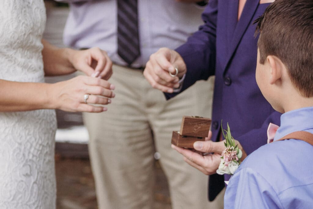 Couple exchanging wedding rings outdoors under gazebo