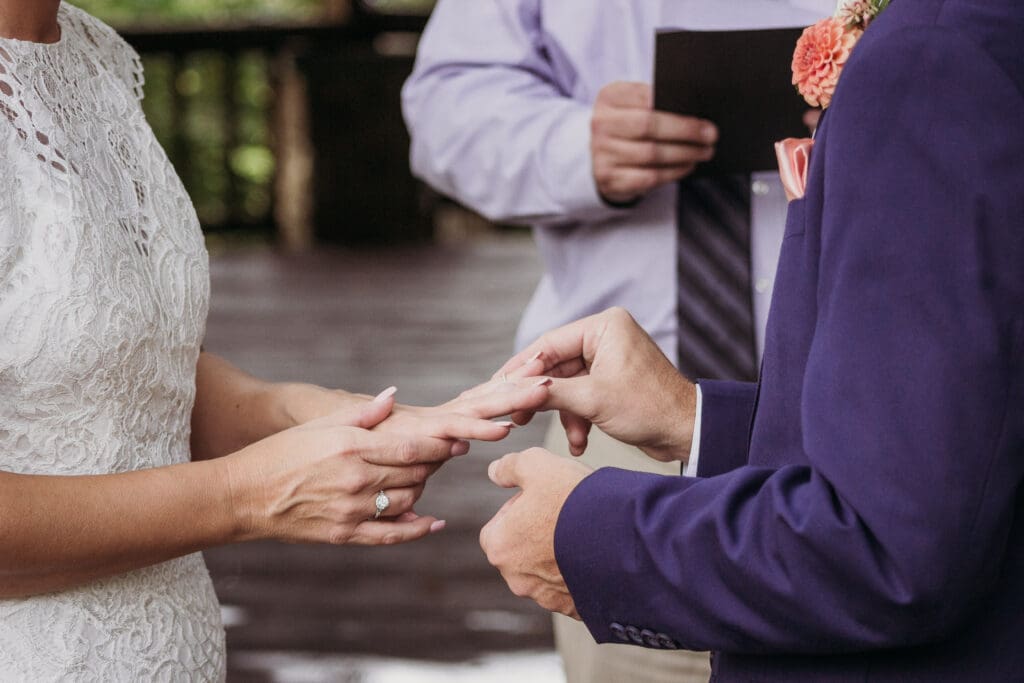 Couple exchanging wedding rings outdoors under gazebo