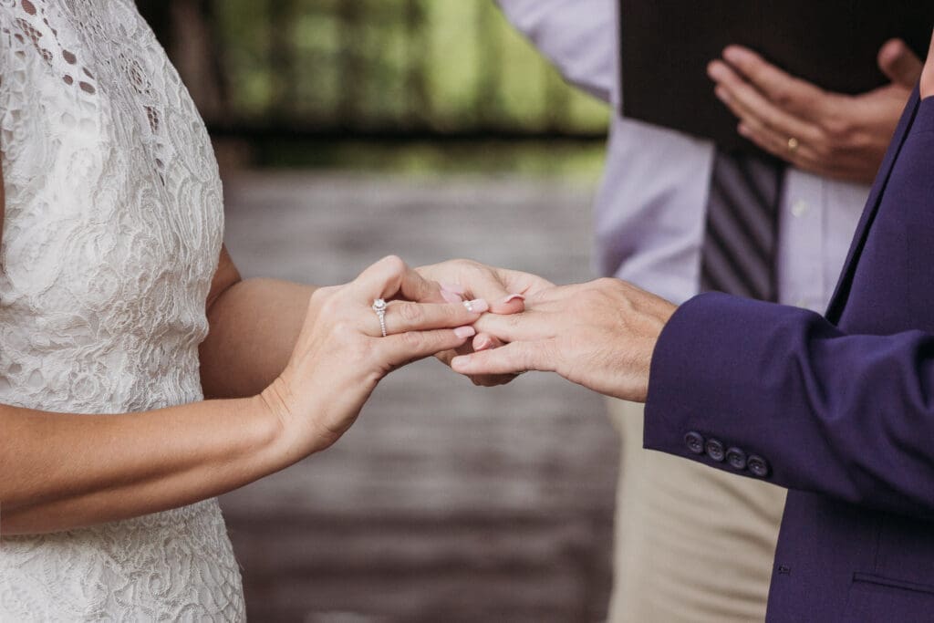 Couple exchanging wedding rings outdoors under gazebo