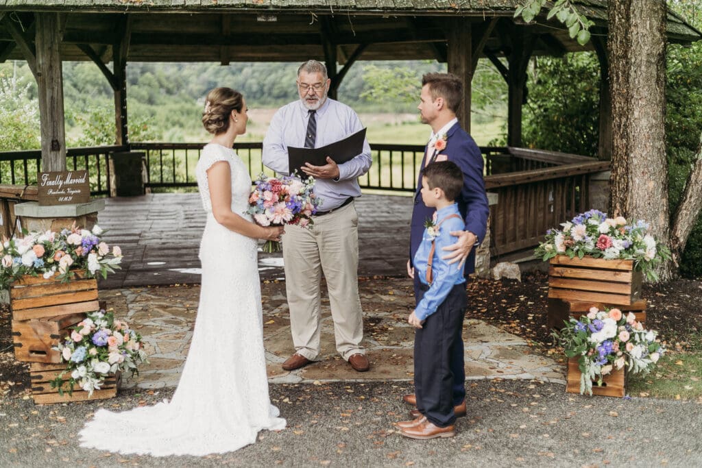 Couple getting married under gazebo eloping in front of the mountains with their son.